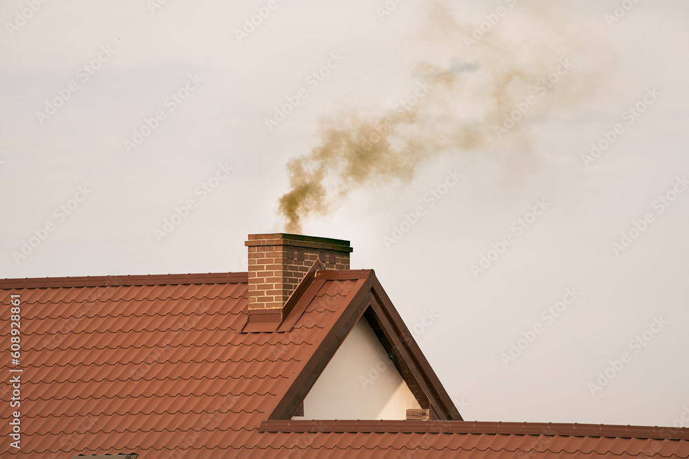 Foto de Black smoke comes out of a modern house chimney. The concept of