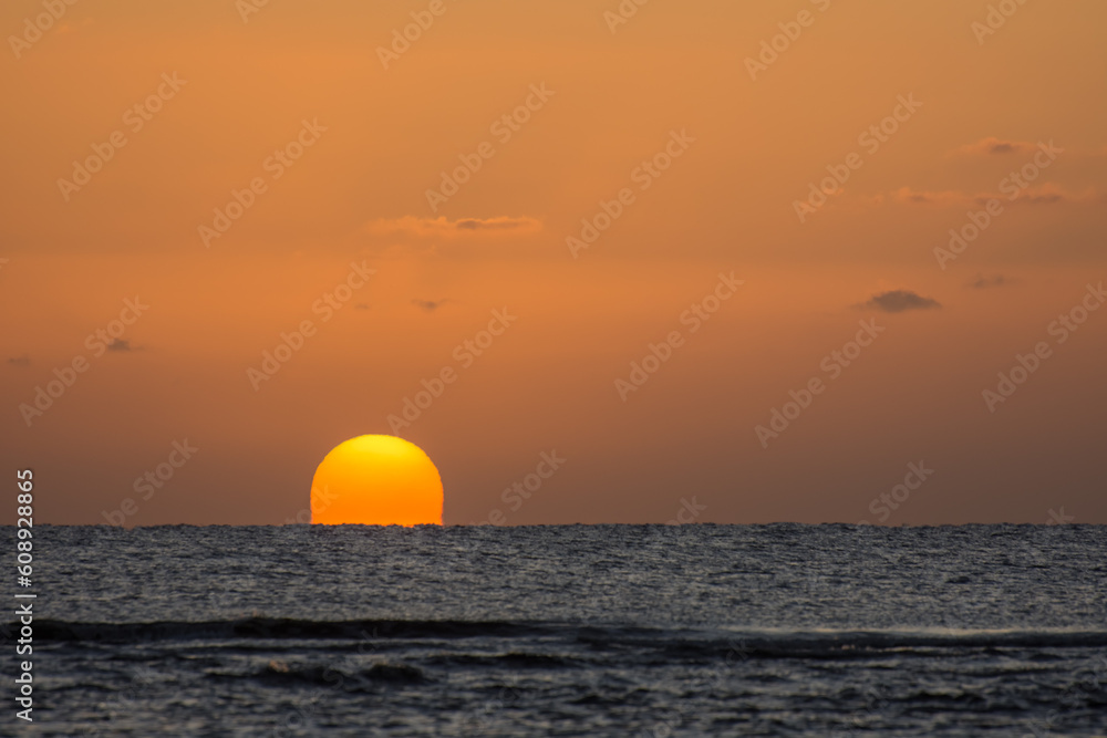 sunrise with a distorted orange sun at the horizon from the red sea in egypt