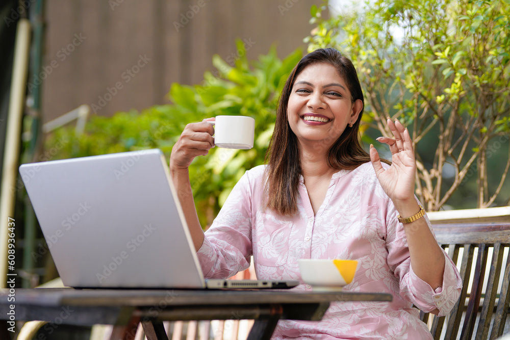 Indian woman using laptop and giving expression while drinking tea or coffee. Indian woman using laptop and giving expression while drinking tea or coffee.