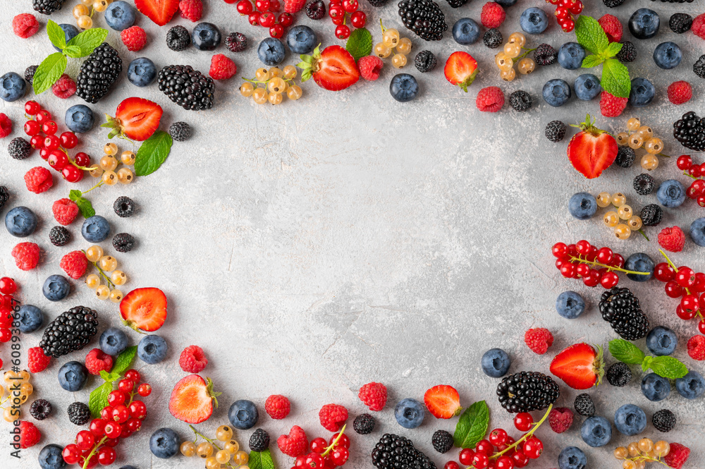 Various fresh summer berries on a gray concrete background. Healthy food concept. Top view. Food background. Various fresh summer berries on a gray concrete background. Healthy food concept. Top view. Food background.