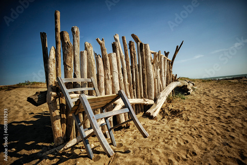 Old wooden chair leaning against the fence on the beach.