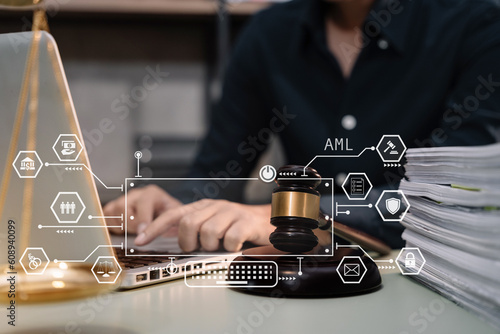 Fotografie Judge in a courtroom using laptop and tablet with AML anti money laundering icon on virtual screen