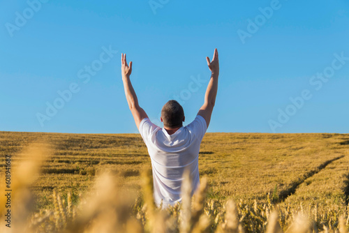 A man in a white T-shirt has raised his hands high to the sky and is harvesting grain. The food crisis in the world.