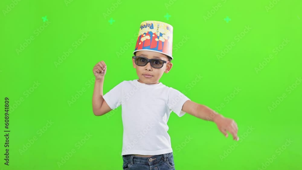 Cool little african american boy in sunglasses dancing with bucket for popcorn on head in motion. Front view of stylish little male kid having fun, joking, isolated on green. Leisure, fun concept. Cool little african american boy in sunglasses dancing with bucket for popcorn on head in motion. Front view of stylish little male kid having fun, joking, isolated on green. Leisure, fun concept.