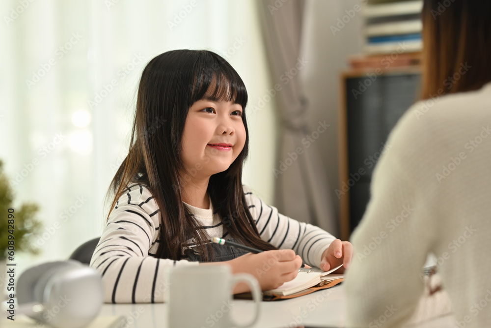 Cute Asian schoolgirl doing home working with tutor at home. Homeschooling and learning concept Cute Asian schoolgirl doing home working with tutor at home. Homeschooling and learning concept