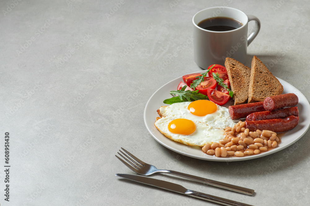 Fried eggs with sausages and beans in a plate on a gray background. English breakfast