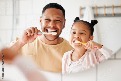 Child, dad and brushing teeth in a family home bathroom for dental health and wellness in a mirror. Face of african man and girl kid learning to clean mouth with toothbrush and smile for oral hygiene photo