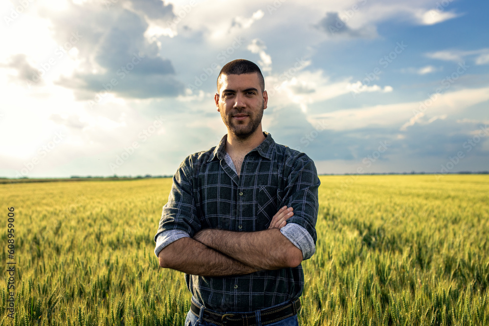 Portrait of young farmer standing in a green wheat field examining crop. Portrait of young farmer standing in a green wheat field examining crop.