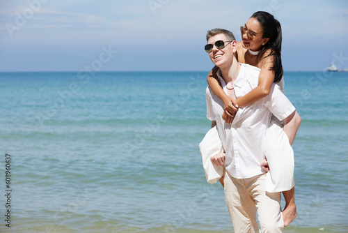happy young man carrying his girlfriend on the beach and enjoy honeymoon in summer