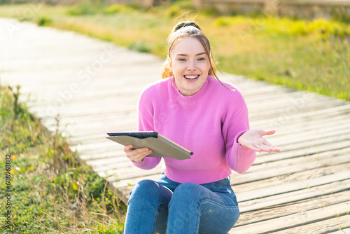 Young pretty girl holding a tablet at outdoors with shocked facial expression © luismolinero