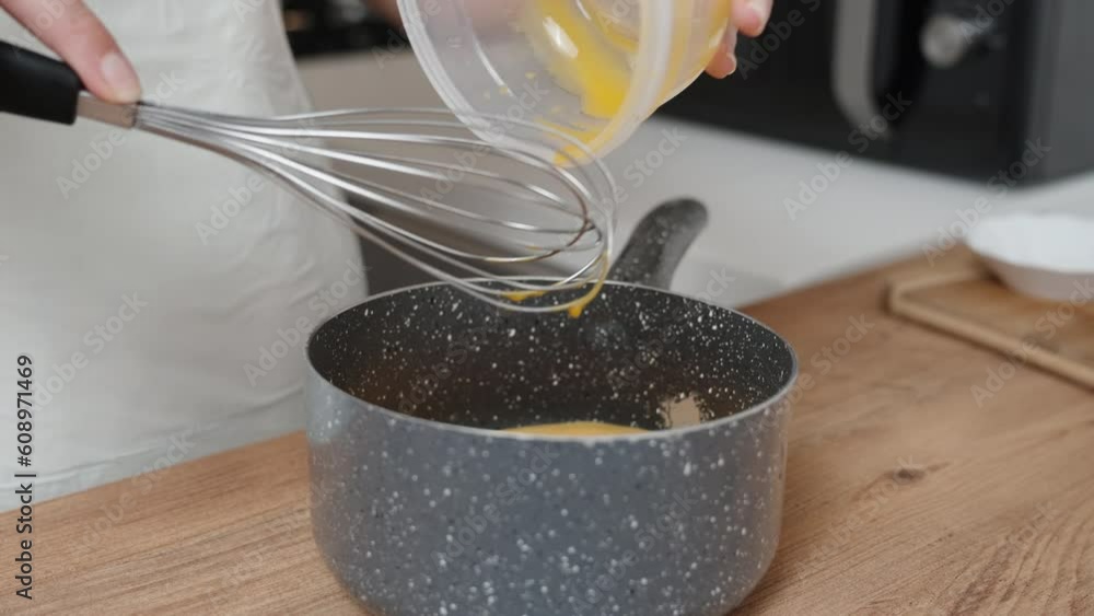 The cook slowly pours the egg yolk into the saucepan. The cook slowly pours the egg yolk into the saucepan.