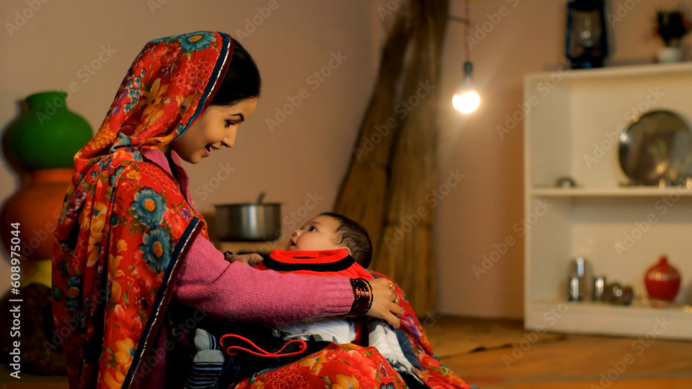 A cheerful village lady with her newborn baby - village home  caring mother  winter season  single mother. An attractive woman spends quality time with her child - family bonding  new generation  a...