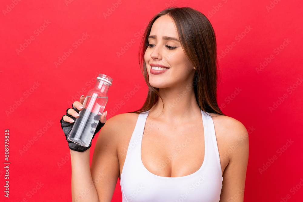 Young beautiful caucasian woman isolated on red background with sports water bottle Young beautiful caucasian woman isolated on red background with sports water bottle