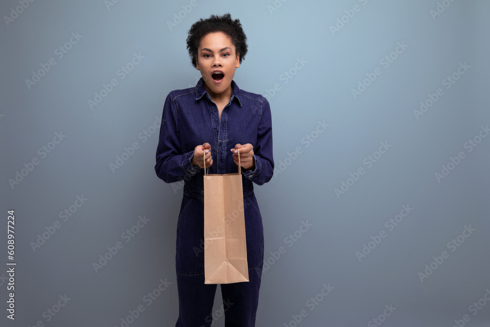 young pretty brunette latin woman with ponytail afro hair dressed in denim received delivery in eco friendly kraft bag young pretty brunette latin woman with ponytail afro hair dressed in denim received delivery in eco friendly kraft bag
