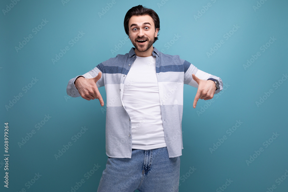 ambitious young brunette man in a sweater with a strong physique points a finger at the news on a studio background ambitious young brunette man in a sweater with a strong physique points a finger at the news on a studio background