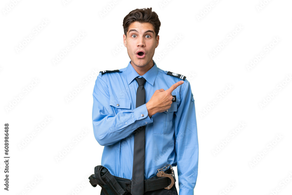 Young police man over isolated background surprised and pointing side Young police man over isolated background surprised and pointing side