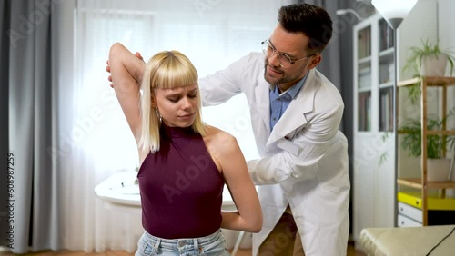 A chiropractor is treating a young woman as a patient in his office. photo