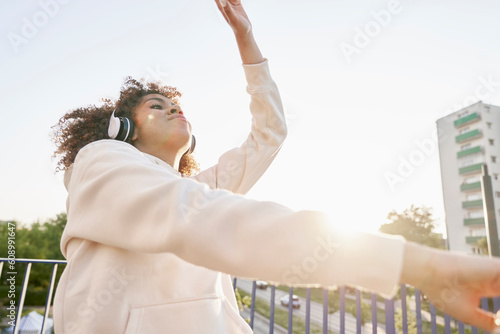 Black woman wearing headphones and dancing on the bridge
