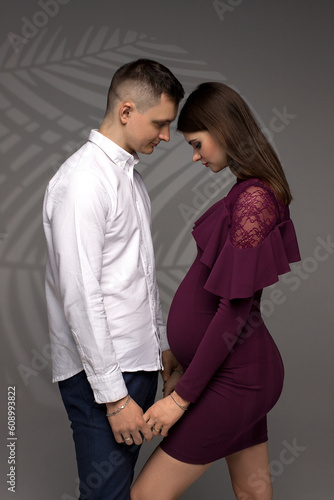 portrait of a pregnant couple on a grey background, studio pregnancy shoot