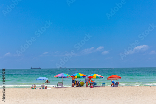 people enjoy sitting in beach chaires with parasol at the fine sand of south beach, Miami photo