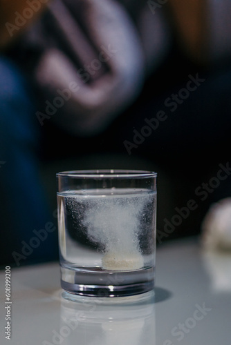 Man putting a pill in the glass of water.