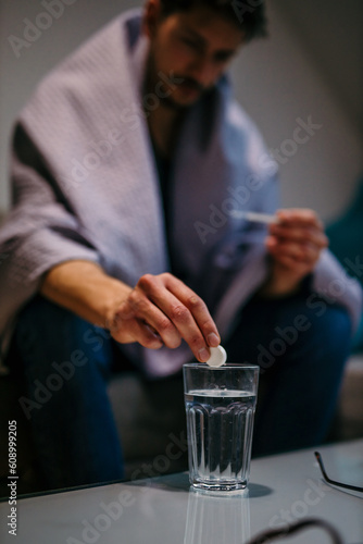Man putting a pill in the glass of water.