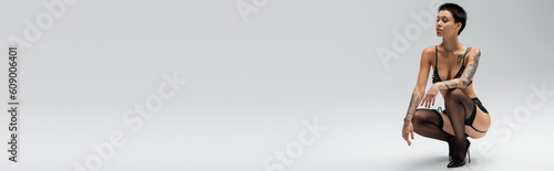 Foto full length of young and desirable tattooed woman with short brunette hair posin