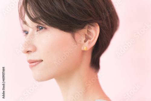 微笑んでいるショートヘアの日本人女性/ピンク背景ビューティーポートレート