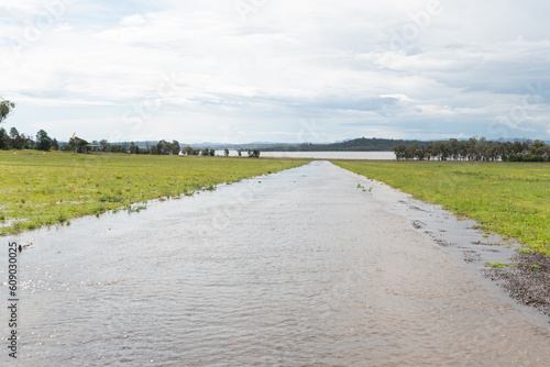 Flood water flowing down a road towards a lake after heavy rain shower