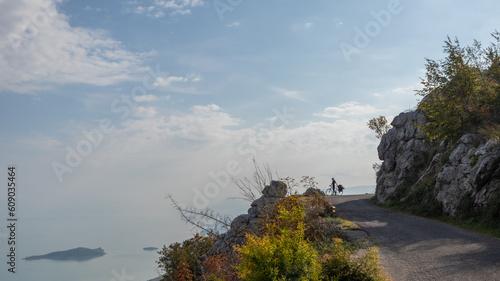 Cyclist standing on the side of mountain overlooking Lake Skadar in Montenegro.  © microice