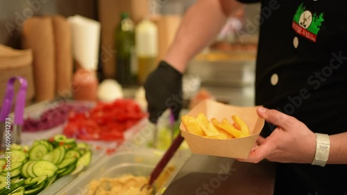 Putting french fries and salad into a food box to serve gyros