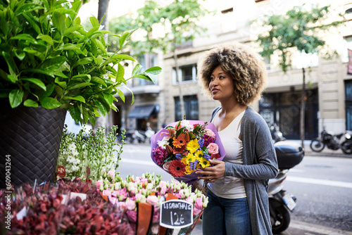 Hispanic woman buying flowers at city market