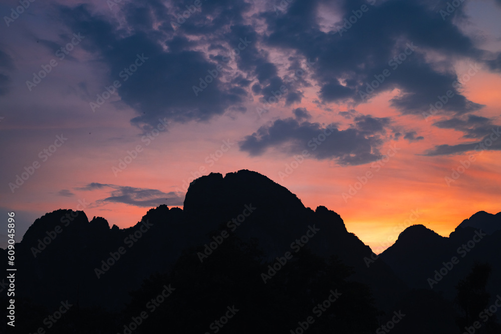 Fototapeta premium Mountain as the sun sets. Mountain peak green nature scenery. Beautiful sunset over the mountain range at vang vieng.