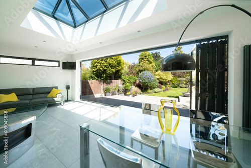 View from interior of designer, lifestyle, open-plan room through open bifold doors to beautiful patio and garden on summer day. photo