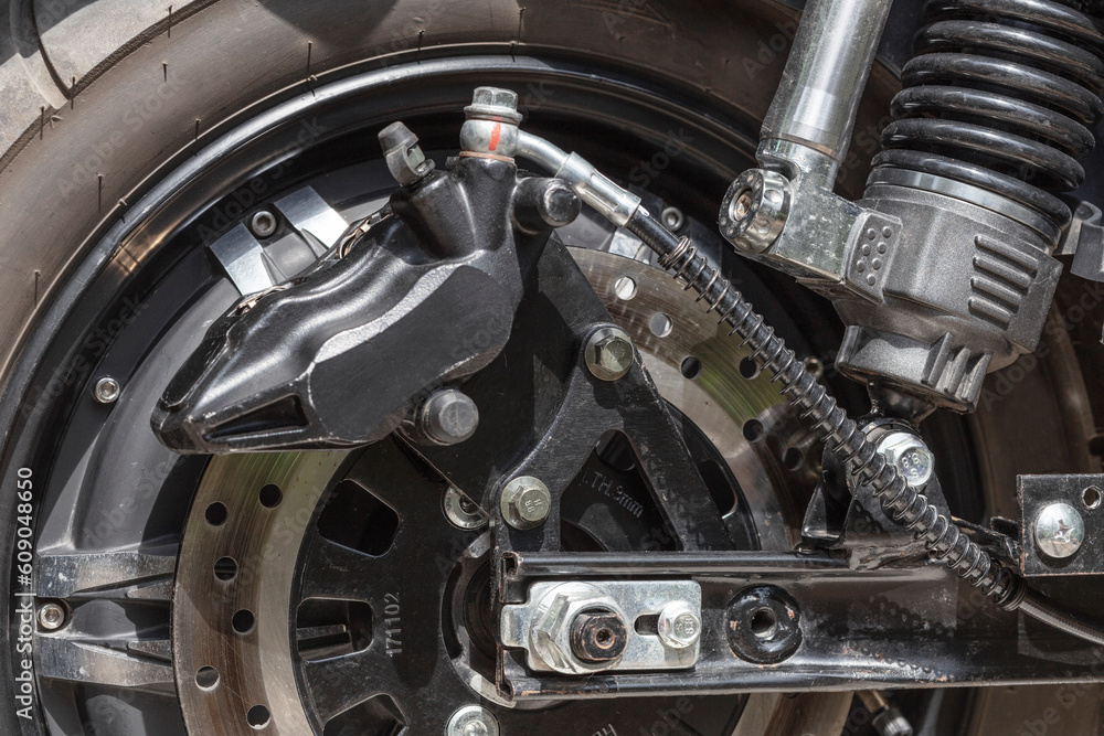 electric motorcycle rear wheel, brake disc and caliper, close up electric motorcycle rear wheel, brake disc and caliper, close up