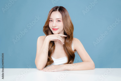 Young Asian beauty woman curly long hair with korean makeup style on face and perfect clean skin on isolated blue background. Facial treatment, Cosmetology, plastic surgery. photo