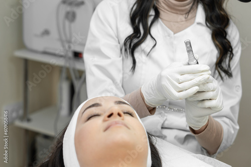 The beautician is preparing to carry out fractional mesotherapy  introducing nutrients to improve complexion  narrow pores and reduce pigmentation. A young woman in a beauty clinic on the procedure.