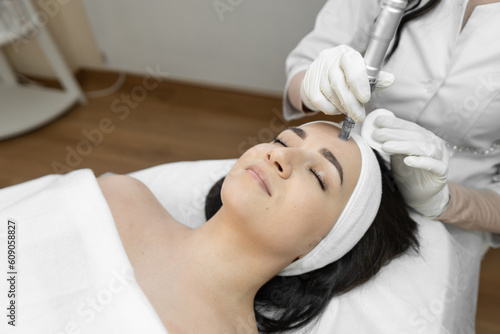 A professional cosmetologist uses innovative fractional mesotherapy to improve the condition of the skin in a beauty salon. The young woman is relaxed and rests during cosmetic procedures.