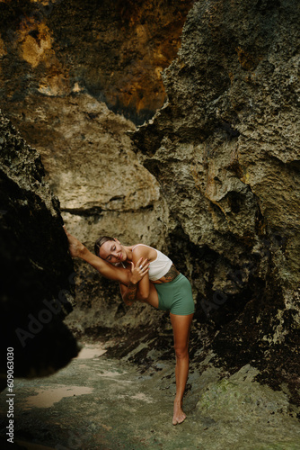 Flexible fit girl exercising by the ocean, fit woman doing leg stretch asana pose keeping vitality of well being and positive body lifestyle. Healthy lifestyle, harmony with nature, yoga and sports