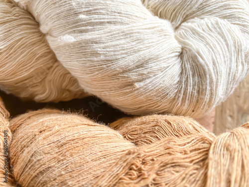 Close-up photo of brown and white cotton thread yarn on wooden table before winding. Plant hemp linen rope wool spool. Concept for traditional handmade textile, small industry, old fashioned, vintage. photo
