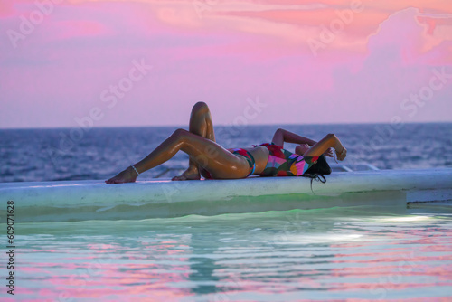 girl lying in a infinity pool at sunset