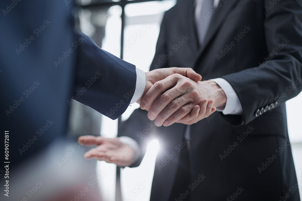 businessmen meeting and handshake in front of business center buildings