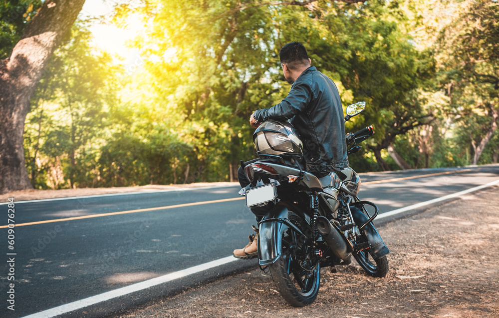 Obraz premium Biker sitting on his motorcycle at the side of the road. Man sitting on his motorcycle at the side of the road