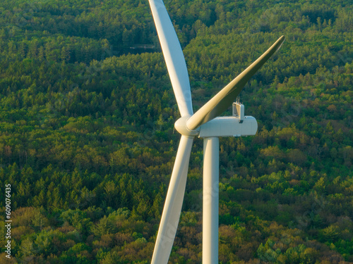 Afternoon aerial drone view of wind power turbines under construction, on a green forest. Wind turbines are part of the energy transition strategy 