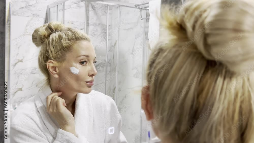 middle aged woman touching face skin looking in mirror reflection. Smiling mature woman pampering, healthy moisturized skin care, aging beauty, skincare treatment cosmetics concept.. middle aged woman touching face skin looking in mirror reflection. Smiling mature woman pampering, healthy moisturized skin care, aging beauty, skincare treatment cosmetics concept..