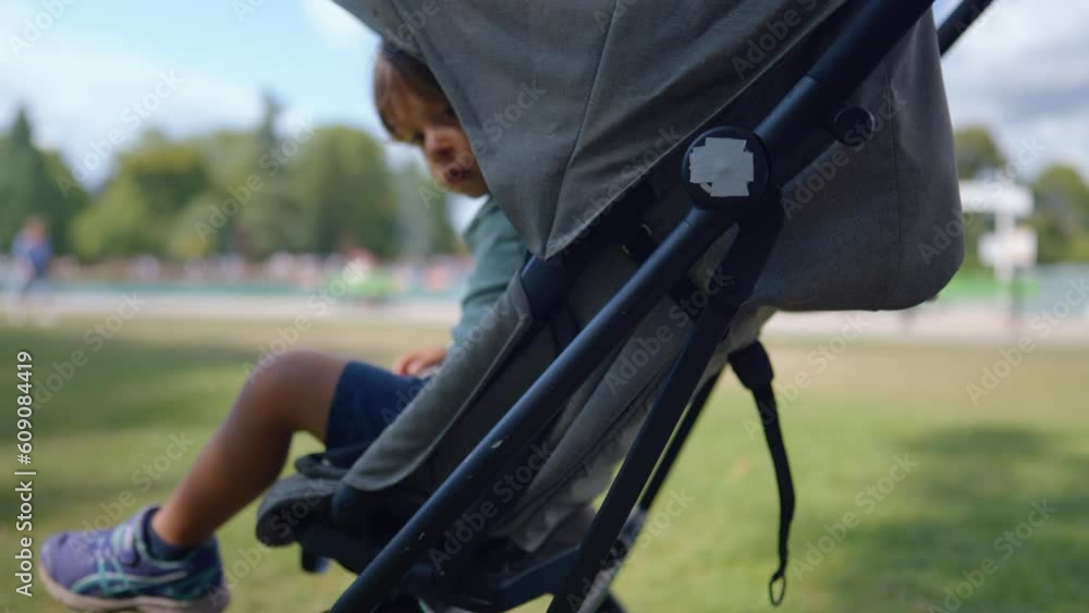 Child waking up from nap inside stroller at park outdoors. One small boy getting up from baby chair carriage during sunny afternoon Child waking up from nap inside stroller at park outdoors. One small boy getting up from baby chair carriage during sunny afternoon