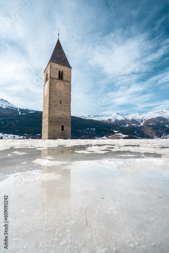 Winter scene at Resia Lake  with sunken gray steeple. Resia Lake is an artificial lake located in the western portion of South Tyrol, Italy, near the Resia Pass.