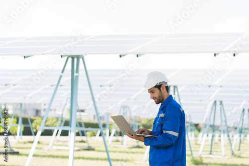 Male engineer worker holding laptop computer working in solar panels power farm. Technician working at solar power station with laptop computer