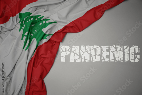 waving colorful national flag of lebanon on a gray background with broken text pandemic. concept. photo