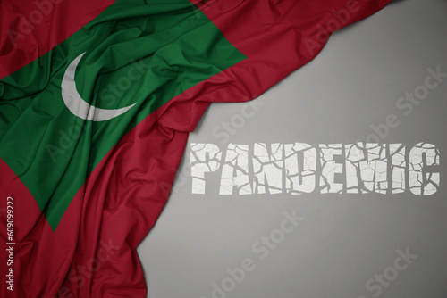 waving colorful national flag of maldives on a gray background with broken text pandemic. concept.